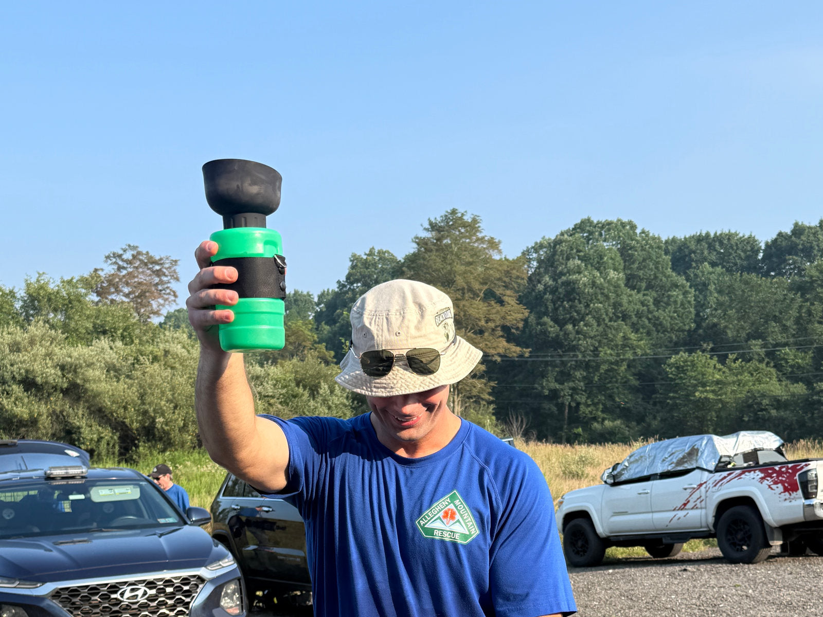 Allegheny Mountain Rescue Group member holding a donated portable K9 water bottle at a training site